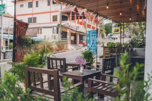 une terrasse avec des tables et des chaises en bois et des fleurs violettes dans l'établissement Chill Inn Chaweng Island Cafe and Hostel, à Ban Nai Na