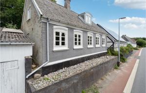 una casa grigia con finestre bianche su una strada di 2 Bedroom Pet Friendly Home In rskbing a Ærøskøbing