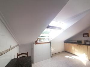 an attic kitchen with a table and a window at Ático 3 hab en centro de Cangas in Cangas de Onís