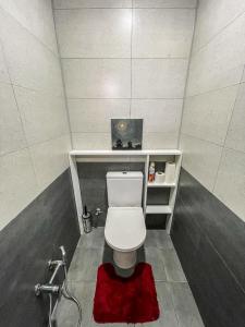 a bathroom with a white toilet and a red rug at Guest house in Qusar