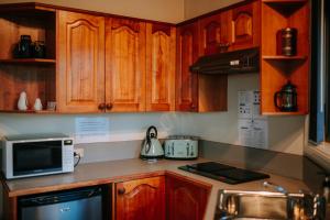 a kitchen with wooden cabinets and a microwave oven at Federation Gardens & Possums Hideaway in Blackheath