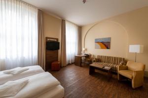 a hotel room with a bed and a couch at Hotel am Großen Waisenhaus in Potsdam