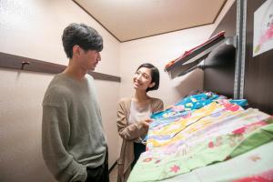 un hombre y una mujer de pie junto a una cama en Yuyado Ichibanchi en Atami