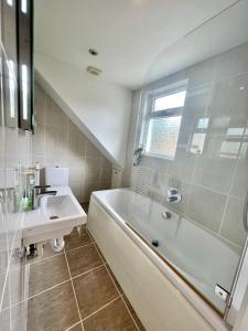 ein Bad mit einer Badewanne, einem Waschbecken und einer Dusche in der Unterkunft Family home in Hampshire - Sleeps up to 9 people with 3 parking spaces in Winchester