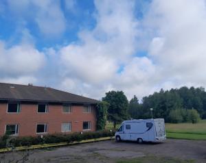 une camionnette blanche garée dans un parking à côté d'un bâtiment dans l'établissement Hostel Svedjegården, à Nybble