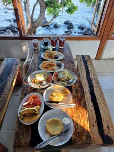 a wooden table with plates of breakfast food on it at Cassabonelly in Maumere