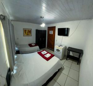 Habitación pequeña con 2 camas y TV en Hotel Anápolis, en Anápolis