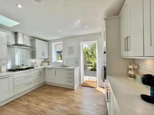 a kitchen with white cabinets and a large window at Family home in Hampshire - Sleeps up to 9 people with 3 parking spaces in Winchester