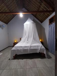un letto a baldacchino bianco in una camera di Cassabonelly a Maumere