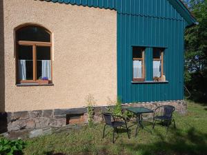 2 Stühle und ein Tisch vor einem Haus in der Unterkunft AuszeitOase am sächs. Jakobsweg in Naundorf