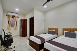 Hotel G.N Palace في كولْكاتا: غرفة نوم بسريرين ومكتب وكرسي