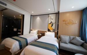 um quarto de hotel com duas camas e um sofá em Puyue Hotel Hangzhou em Hangzhou