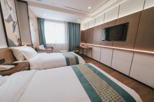 um quarto de hotel com duas camas e uma televisão de ecrã plano em Puyue Hotel Hangzhou em Hangzhou