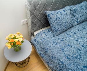Una cama con una manta azul y una mesa con un jarrón de flores en Fort63 apartments, en Kaunas