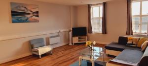 a living room with a couch and a tv at Modern and spacious Swansea centre apartment in Swansea