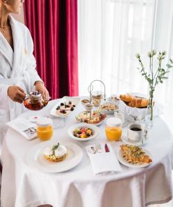 een vrouw aan een tafel met ontbijtproducten bij Venus Hotel in Pristina