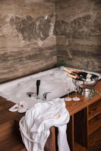 a bath tub with a sink and two wine glasses at Venus Hotel in Prishtinë