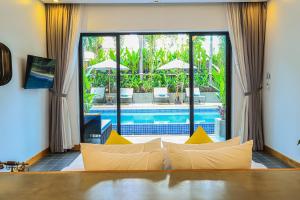 uma sala de estar com um sofá em frente a uma piscina em Grand Yard La Residence em Siem Reap