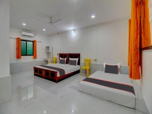 two beds in a white room with orange curtains at Homely Stays Resort in Pune