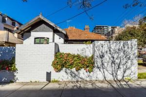 eine weiße Ziegelmauer mit einer Pflanze darauf in der Unterkunft Crows Nest LemonTree Cozy 3 Bedroom House in Sydney