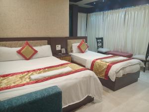 a hotel room with two beds and a chair at The Brahmaputra Hotel in Dhuburi