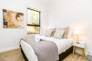 een witte slaapkamer met een bed en een raam bij Crows Nest LemonTree Cozy 3 Bedroom House in Sydney