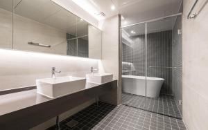 łazienka z 2 umywalkami, wanną i prysznicem w obiekcie The Van Hotel w mieście Gimhae