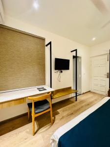 a bedroom with a desk and a bed and a tv at Hotel Mystic Falls in Jaipur