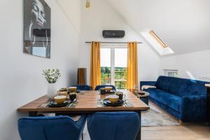 a living room with a wooden table and blue chairs at Exclusive Apartment Różana with AC & Balcony View 1 km to the Beach by Renters in Sianozety