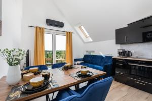 a kitchen and living room with a wooden table and blue chairs at Exclusive Apartment Różana with AC & Balcony View 1 km to the Beach by Renters in Sianozety