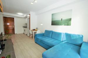 een woonkamer met een blauwe bank en een keuken bij Alquilaencanarias Medano Cabezo Beach in El Médano