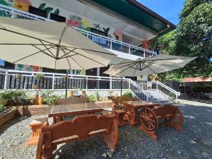 a patio with two tables and an umbrella and a cart at ABODE21 Guesthouse in Balingasay