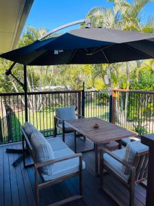 a wooden table and chairs with an umbrella on a deck at GOLDEN LACE B&B in Sarina