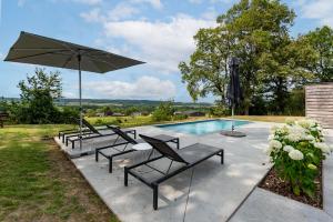- un groupe de chaises et un parasol à côté de la piscine dans l'établissement Gite 1 Maison Caerdinael - Gîte 14 personnes sur les hauteurs de Durbuy, à Durbuy