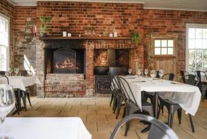 a brick room with tables and chairs and a fireplace at THE BERRY HOTEL in Berry