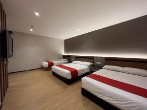 a hotel room with two beds and a flat screen tv at GRAND AROMAS in Kulai