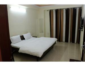 una camera da letto con letto, lenzuola e cuscini bianchi di Hotel Gopi Dham, Haridwar a Haridwār
