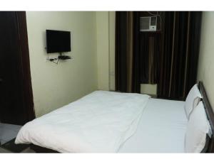 una camera da letto con un letto bianco e una TV a parete di Hotel Gopi Dham, Haridwar a Haridwār