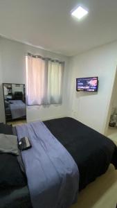 a bedroom with a large bed and a television at Quarto Suíte em apto compartilhado com anfitrião Mandi a 250m do Mar in Itapema