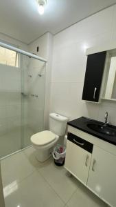 a bathroom with a toilet and a shower and a sink at Quarto Suíte em apto compartilhado com anfitrião Mandi a 250m do Mar in Itapema