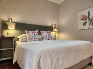 a bedroom with a large white bed with pink pillows at Little Scotia in Cape Town