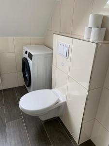 a bathroom with a toilet and a washing machine at DG Apartament in Bersenbrück