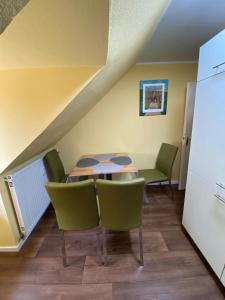 a dining room with a table and green chairs at DG Apartament in Bersenbrück