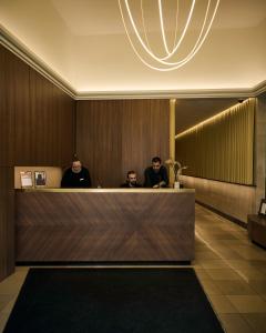 tres hombres sentados en una recepción en un vestíbulo en Melter Hotel & Apartments - a Neighborhood Hotel, en Núremberg