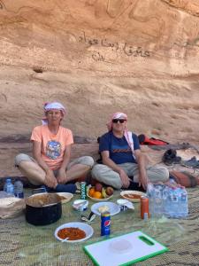 two people sitting on the ground with food and drinks at Wadi Rum Spring Moon & Jeep Tour in Wadi Rum +92 photos