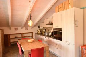 uma cozinha com uma mesa de madeira e cadeiras vermelhas em PM Villa Tania Guest House em Alghero
