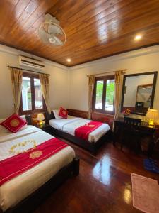 a bedroom with two beds and a mirror at Golden Lotus Boutique Hotel in Luang Prabang