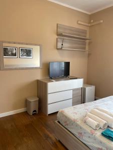 een slaapkamer met een bed en een dressoir met een televisie bij T-Rooms in Cagliari