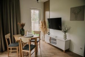 ein Wohnzimmer mit einem Esstisch und einem TV in der Unterkunft Sam Las Apartamenty Białowieża in Białowieża