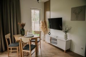 a living room with a dining room table and a tv at Sam Las Apartamenty Białowieża in Białowieża